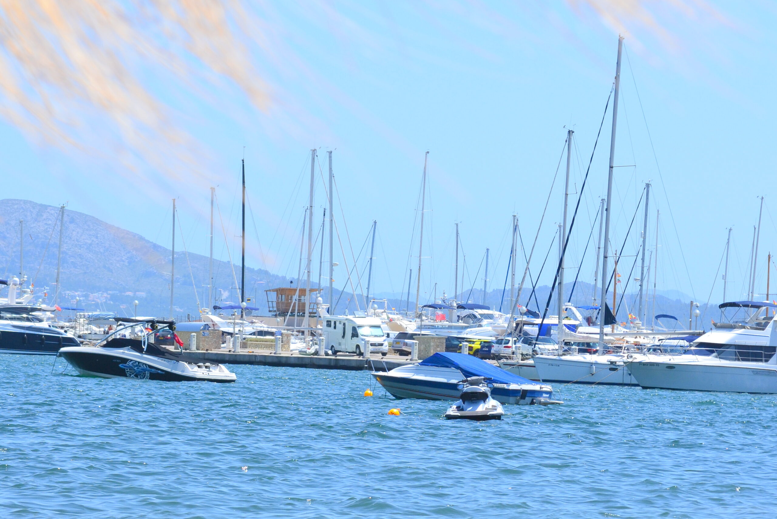 Zeilboten en motorjachten in de jachthaven van Port de Pollença, met de bergen van de Tramuntana op de achtergrond