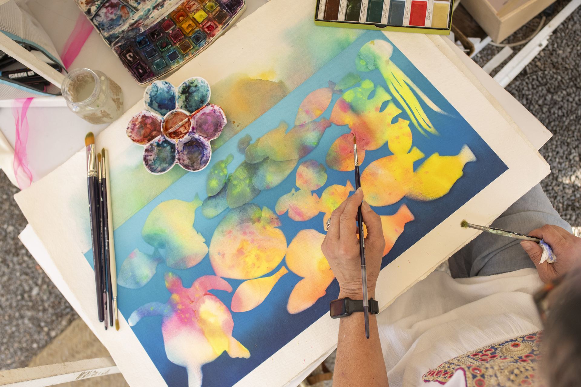 Punta Arabí Ibiza: de oudste hippiemarkt van het eiland, sinds 1973 4 Een kunstenaar schildert met aquarelverf kleurrijke vissen en kwallen op papier aan zijn kraam