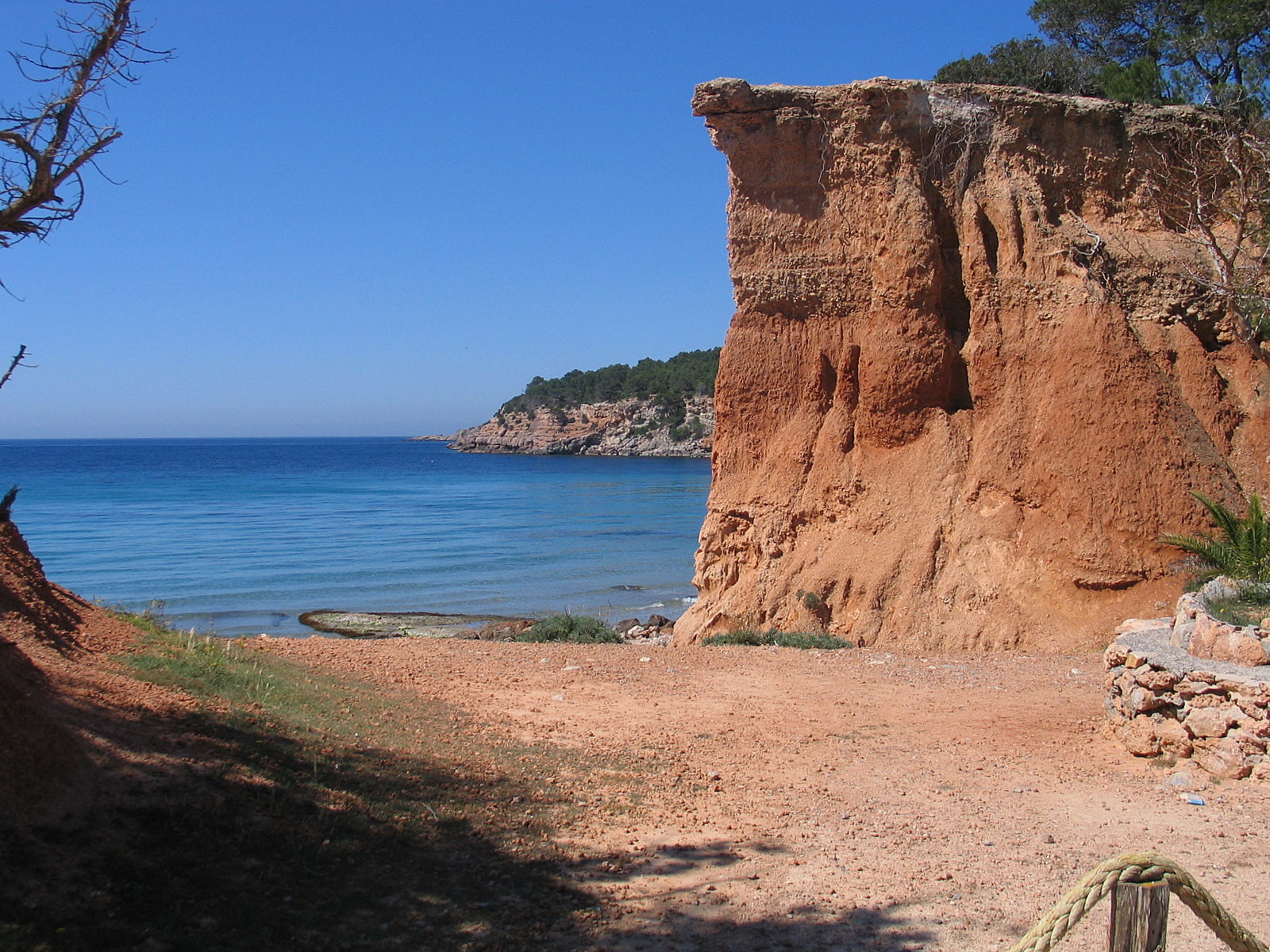 Sa Caleta Ibiza: zuidkust-strand met UNESCO Foenicische nederzetting 5 De roodbruine kliffen van Sa Caleta op Ibiza met daarachter de blauwe zee en de kust van de zuidkust