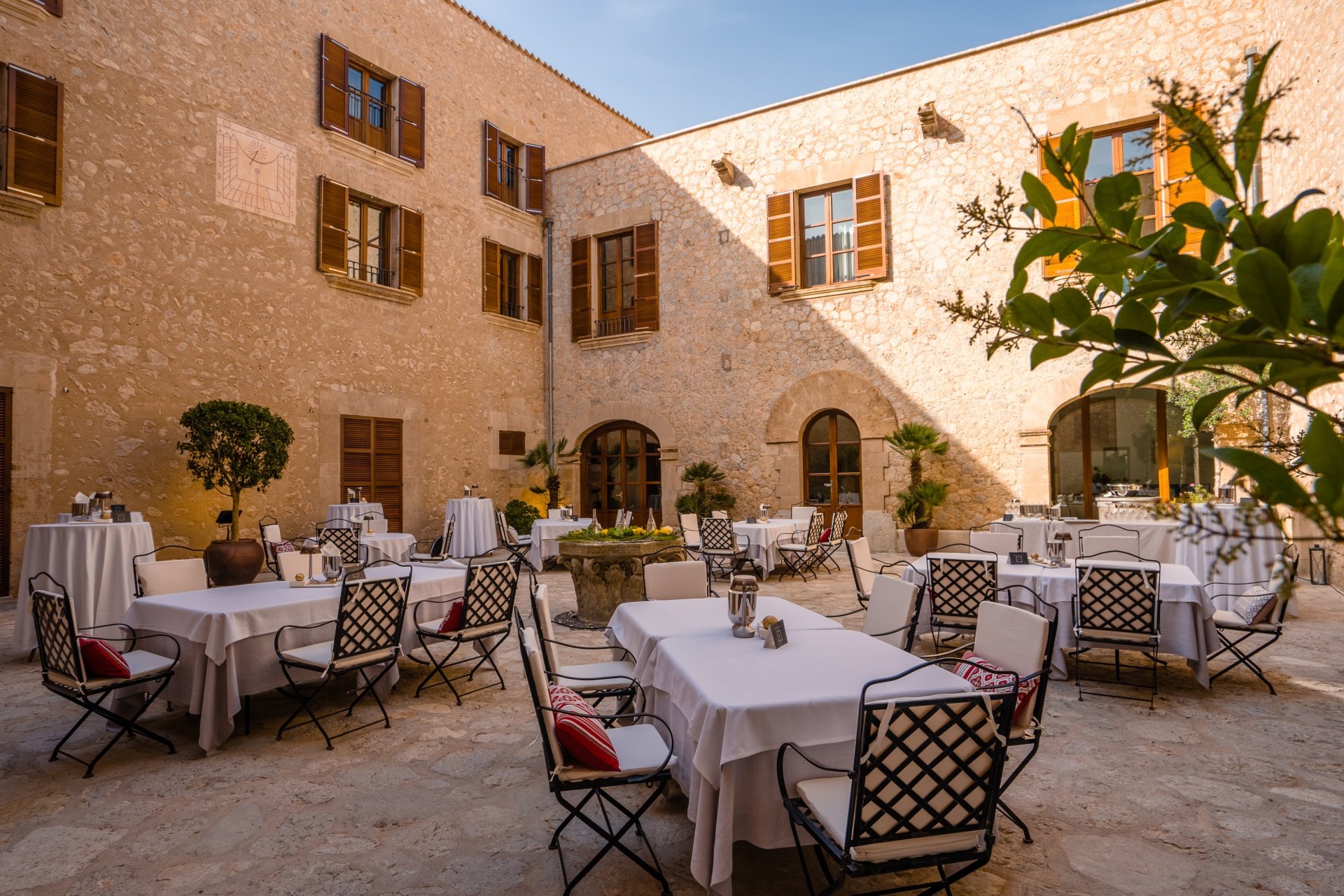 Sa Clastra bij Es Capdellà: een sterrenmenu van negen winden 1 De binnenplaats van restaurant Sa Clastra op landgoed Castell Son Claret op Mallorca, met gedekte tafels tussen honingkleurige muren