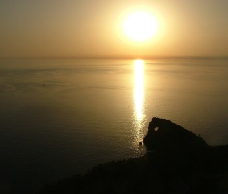 De zon zakt in zee achter het silhouet van Sa Foradada op Mallorca