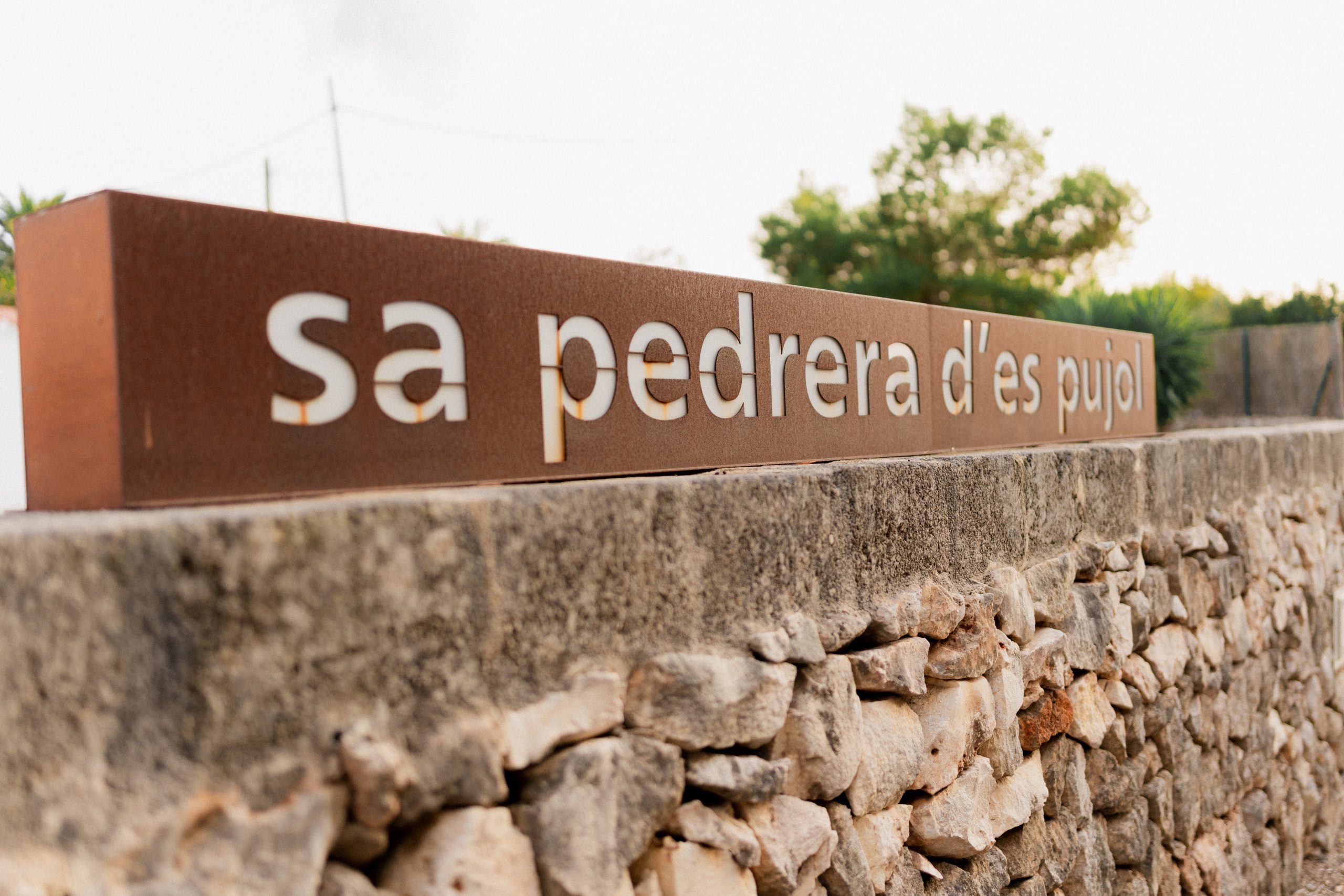 De stenen muur met de naam Sa Pedrera d'es Pujol bij de ingang