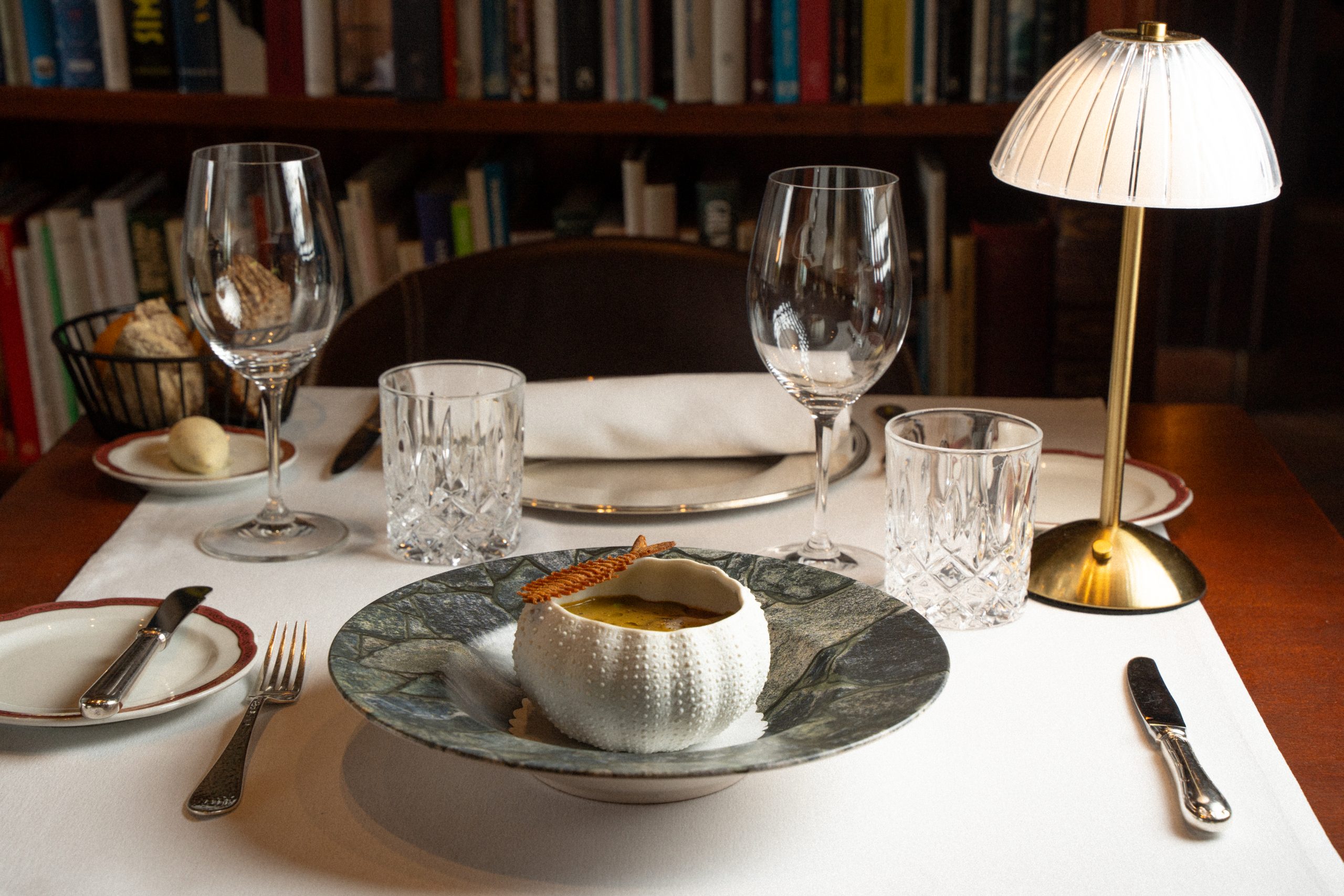 Gedekte tafel met wijnglazen en schemerlamp in de eetzaal van Sa Pedrera d'es Pujol