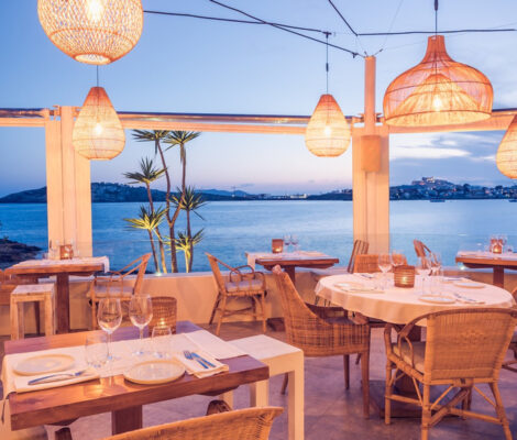 Het terras van Sa Punta bij schemering met hanglampen en uitzicht over de baai van Talamanca