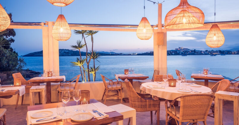 Het terras van Sa Punta bij schemering met hanglampen en uitzicht over de baai van Talamanca