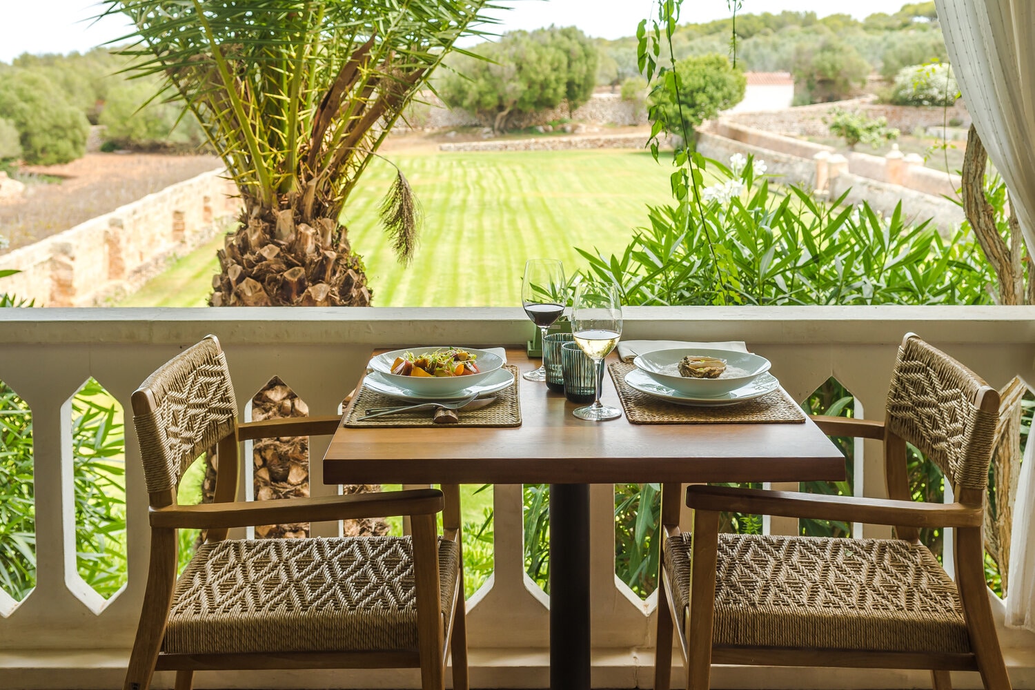 Een gedekte tafel op het terras met uitzicht op de tuin en een palmboom bij Sant Joan de Binissaida