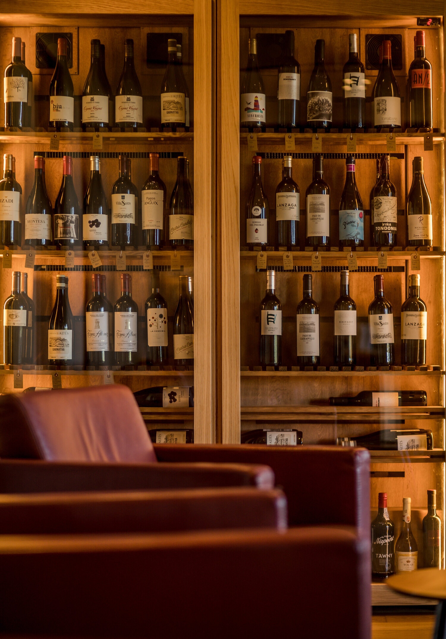 De verlichte wijnkast met leren fauteuils in de salon van Sant Joan de Binissaida