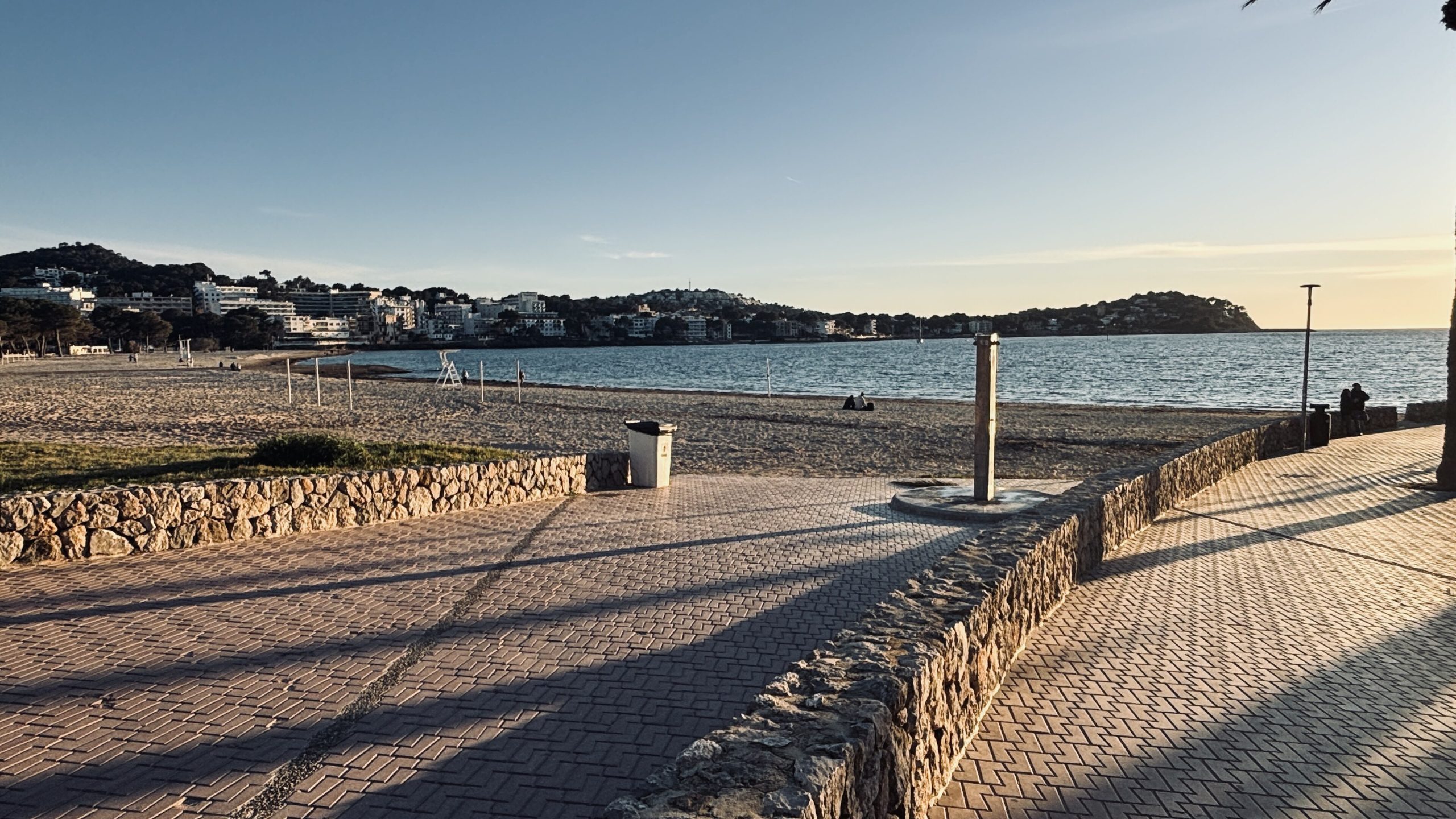 De boulevard langs het strand van Santa Ponça in het late middaglicht, met de baai en de beboste kaap op de achtergrond