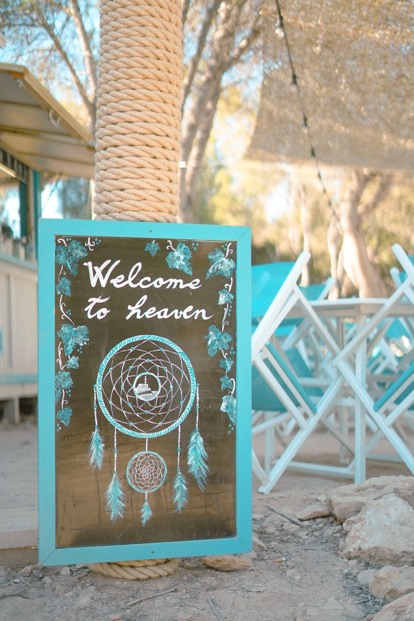 Welkomstbord met de tekst Welcome to heaven bij de ingang van S'Arenal de Portocolom tussen de blauwe stoelen