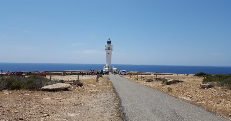 De weg naar de vuurtoren van Cap de Barbaria op Formentera, met geparkeerde scooters bij de vuurtoren