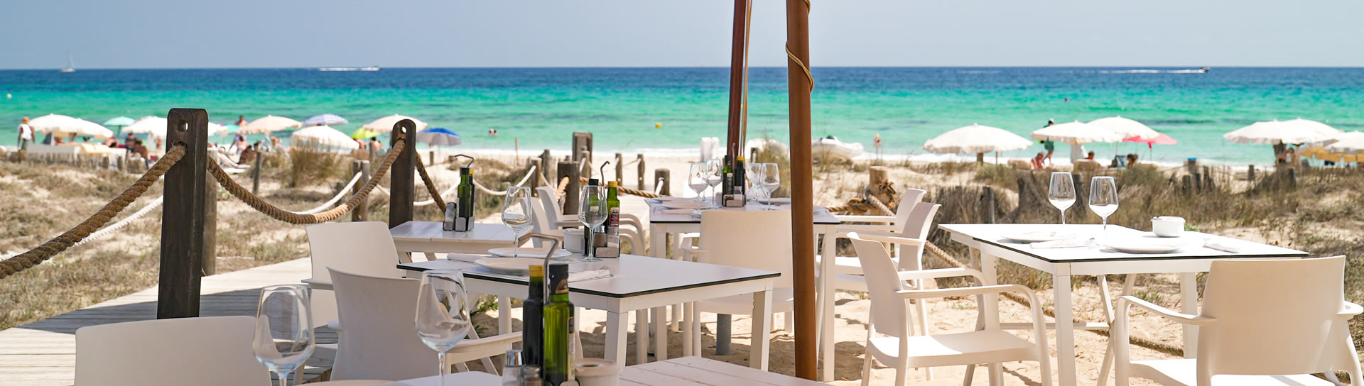 Het terras met gedekte tafels en parasols van Restaurant Tanga aan de zee