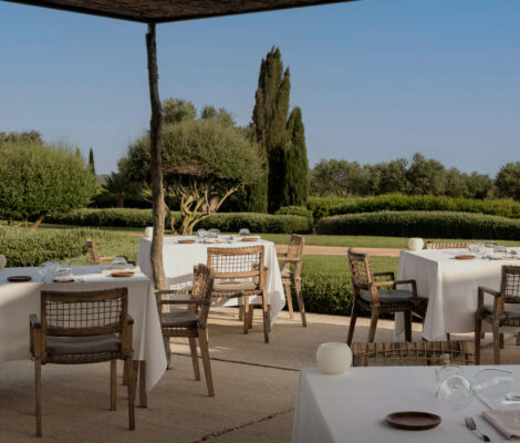 Het buitenterras van restaurant Torralbenc met gedekte tafels en de tuinen van het landgoed erachter