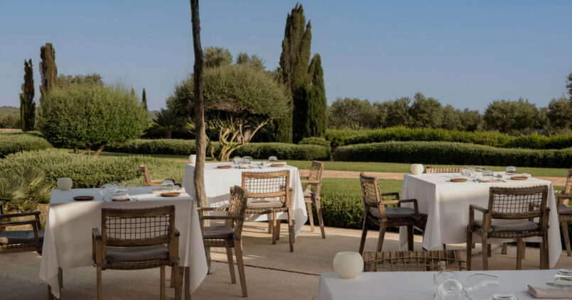 Het buitenterras van restaurant Torralbenc met gedekte tafels en de tuinen van het landgoed erachter
