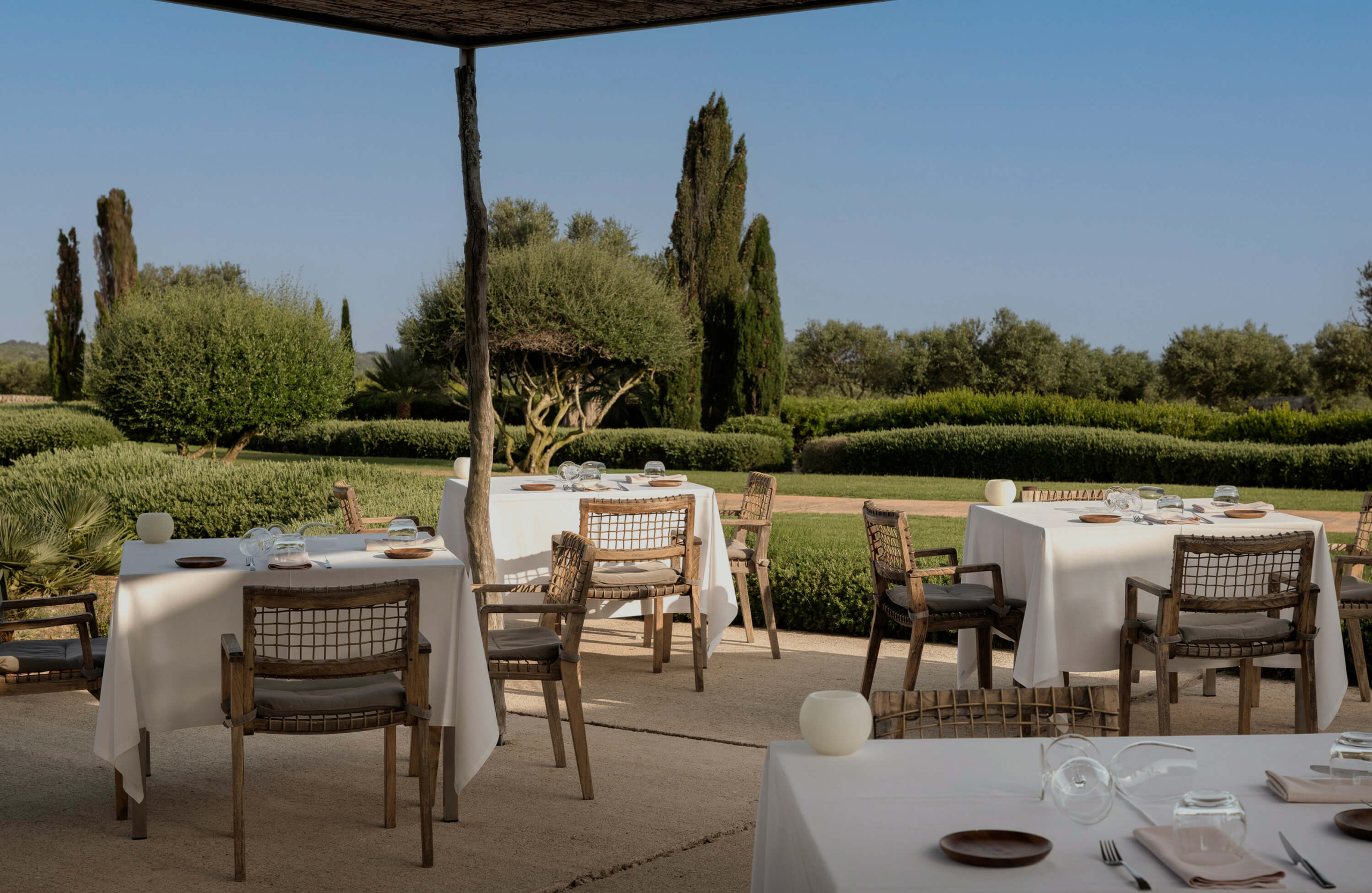 Het buitenterras van restaurant Torralbenc met gedekte tafels en de tuinen van het landgoed erachter