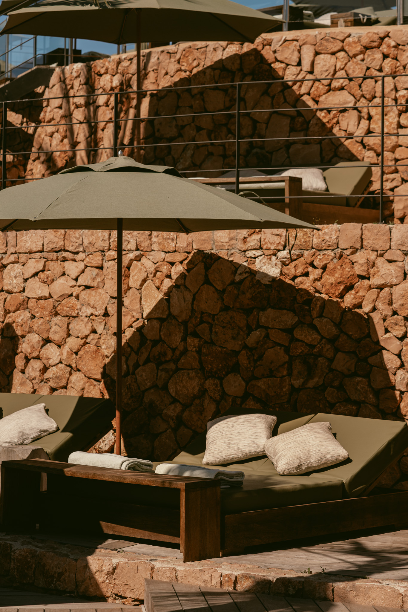 Day bed met kussens onder een parasol op het terras van UM Beach House