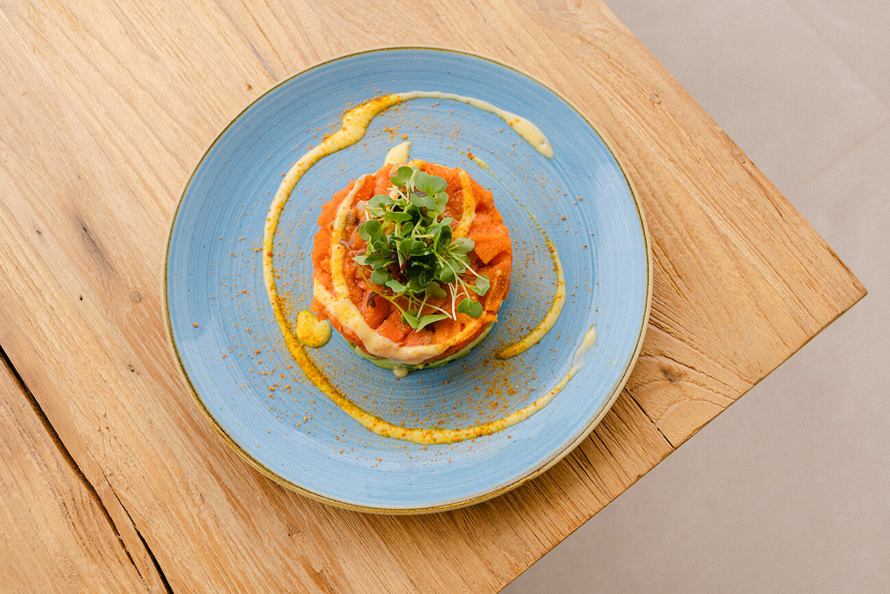 Een verzorgd voorgerecht op een blauw bord bij restaurant Viva La Pepa op Menorca
