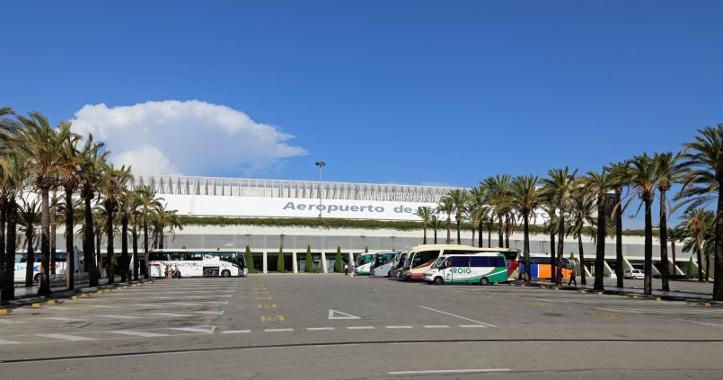 De terminal van het vliegveld van Palma de Mallorca met palmbomen en touringcars voor de deur