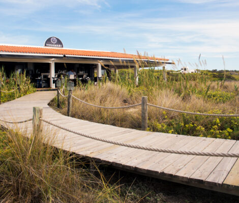 Het strandrestaurant Vogamarí aan Platja de Migjorn, met een houten pad door de duinen naar de zee