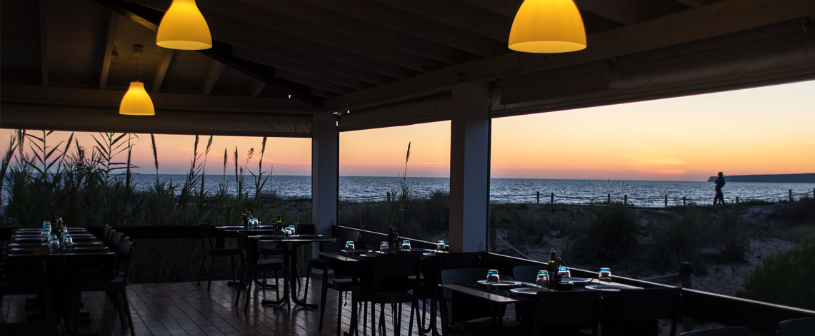 Het overdekte terras van Vogamarí bij zonsondergang met uitzicht op de zee