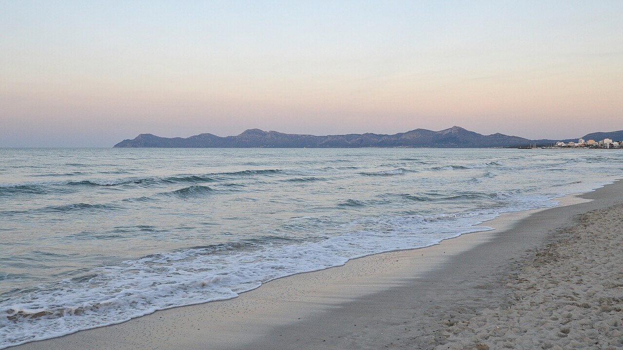 Wanneer boek je een vakantie naar de Balearen het goedkoopst? 3 Het brede zandstrand van Platja de Muro aan de Badia d'Alcúdia op Mallorca, vrijwel leeg in het voorseizoen