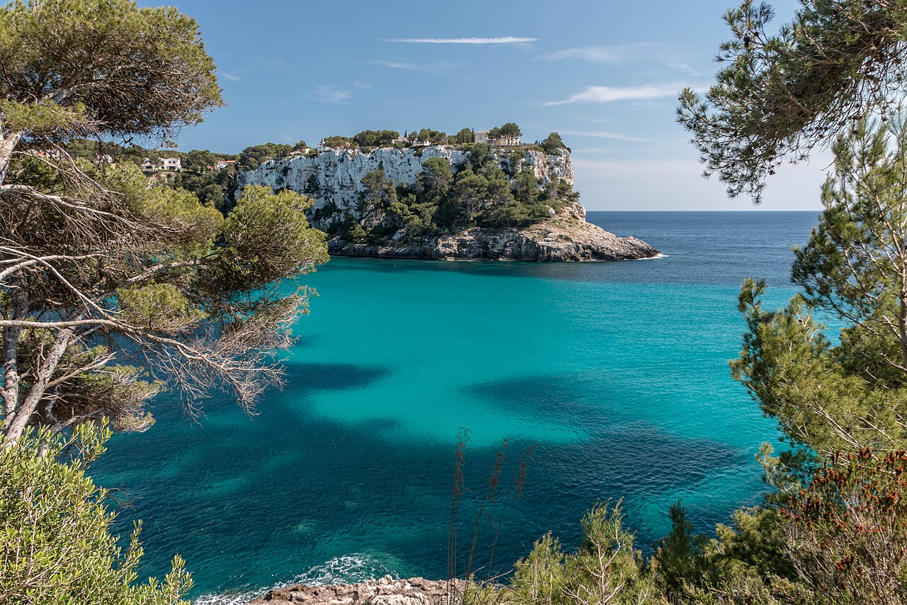 Wanneer boek je een vakantie naar de Balearen het goedkoopst? 5 Het turquoise water van Cala Galdana op Menorca, omringd door dennen op de rotswanden