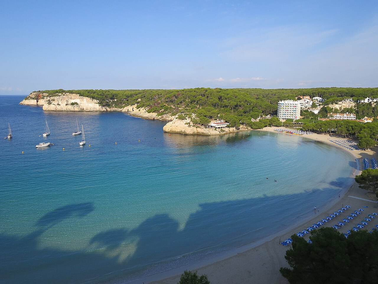 Wanneer boek je een vakantie naar de Balearen het goedkoopst? 6 Het zandstrand van Cala Galdana op Menorca met de beboste landtong die de baai afsluit