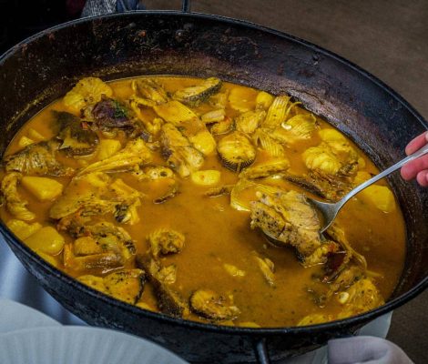 Een pan bullit de peix met stukken vis in een goudgele bouillon, opgeschept bij restaurant Es Nàutic in Sant Antoni op Ibiza
