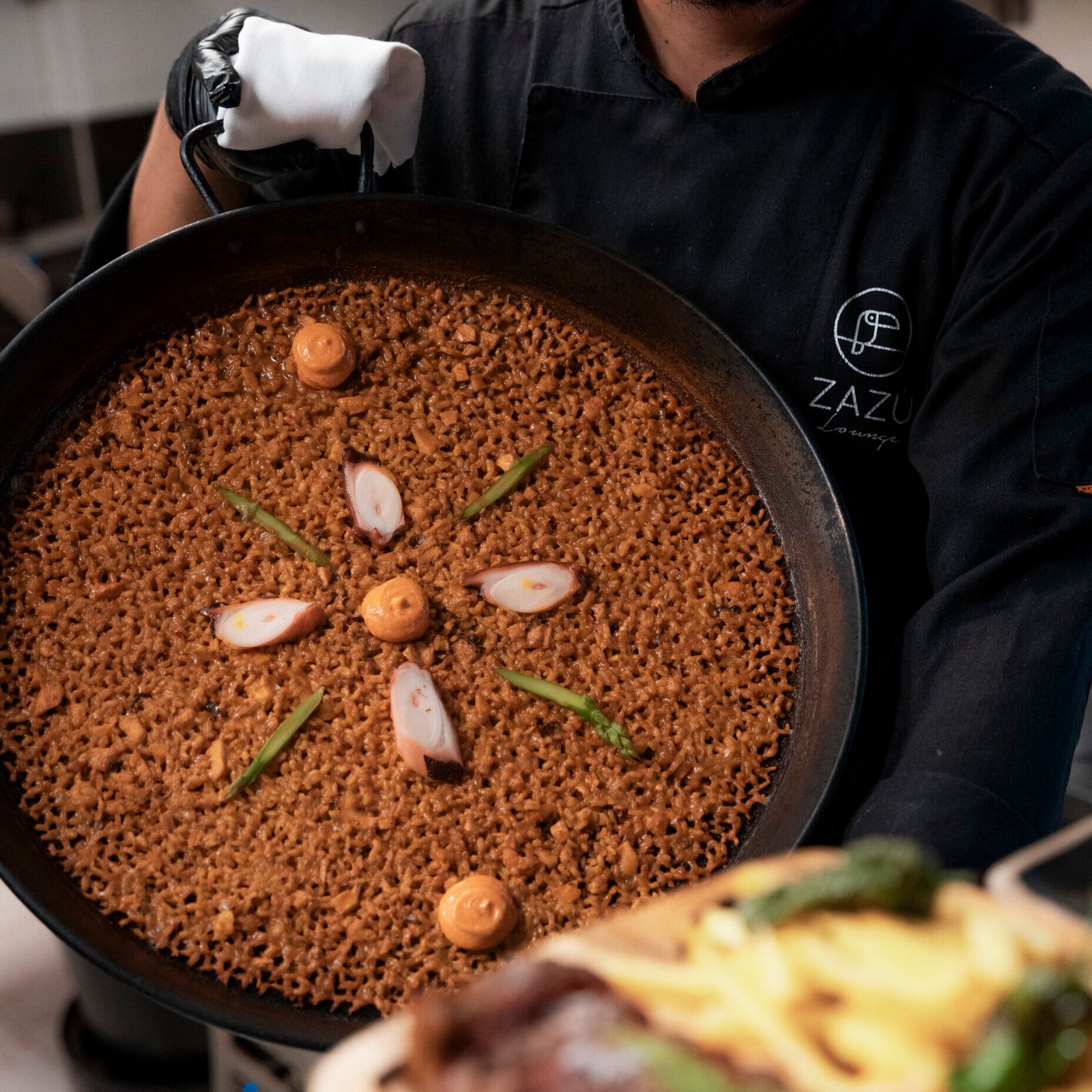 Ober serveert een pan arroz bij Zazú Ibiza