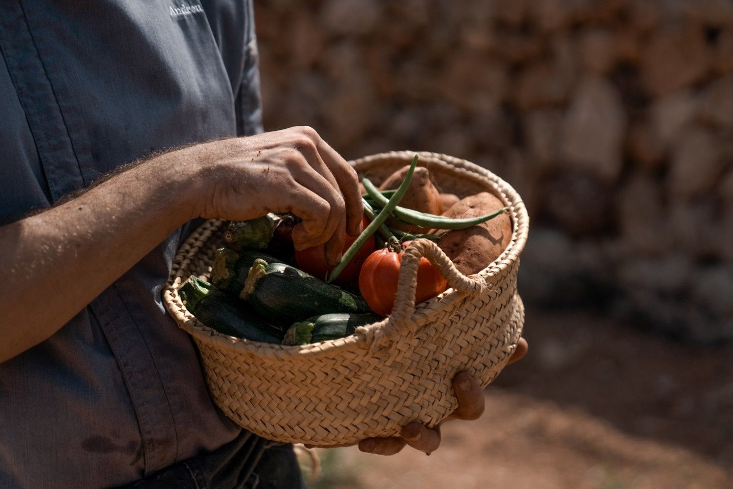 365 bij Son Brull (Pollença): het menu uit de eigen finca 2 Iemand draagt een rieten mand met pas geoogste groente langs de natuurstenen muur van Son Brull