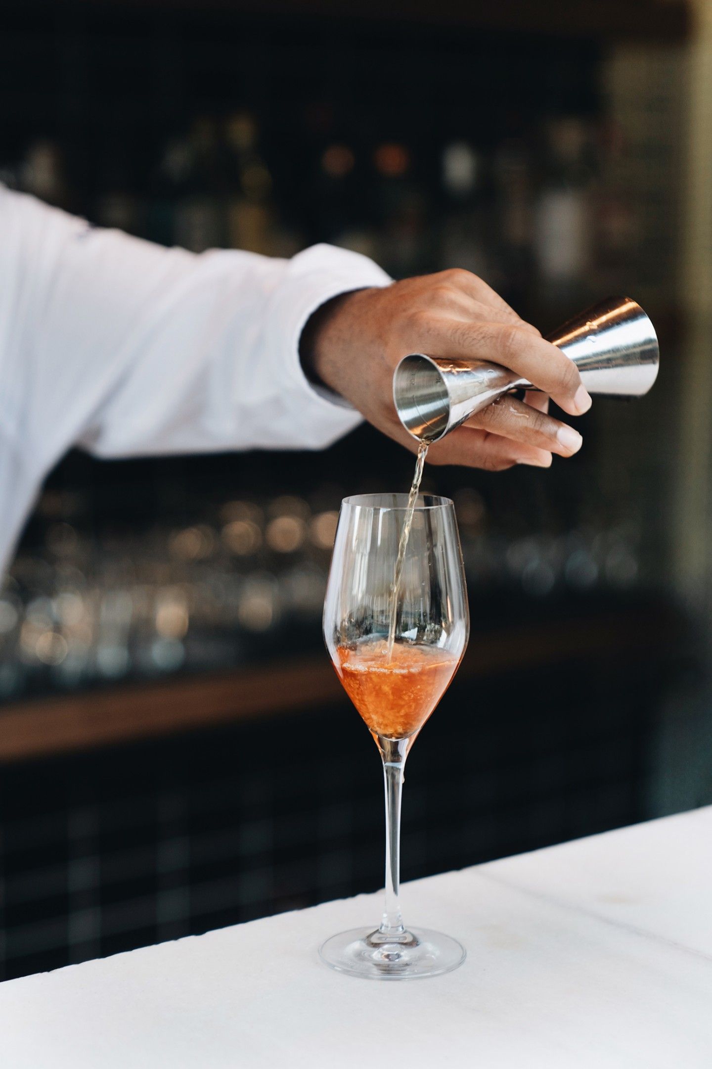 365 bij Son Brull (Pollença): het menu uit de eigen finca 5 Een barman schenkt een oranje cocktail in een glas aan de bar van Son Brull