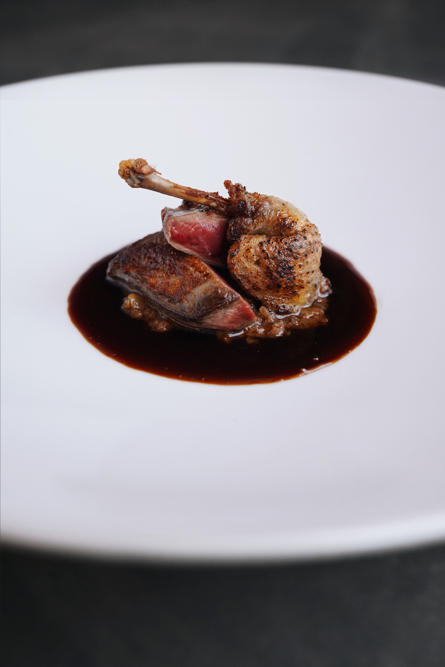 365 bij Son Brull (Pollença): het menu uit de eigen finca 8 Gebraden duif in een donkere jus op een wit bord bij restaurant 365 in Son Brull
