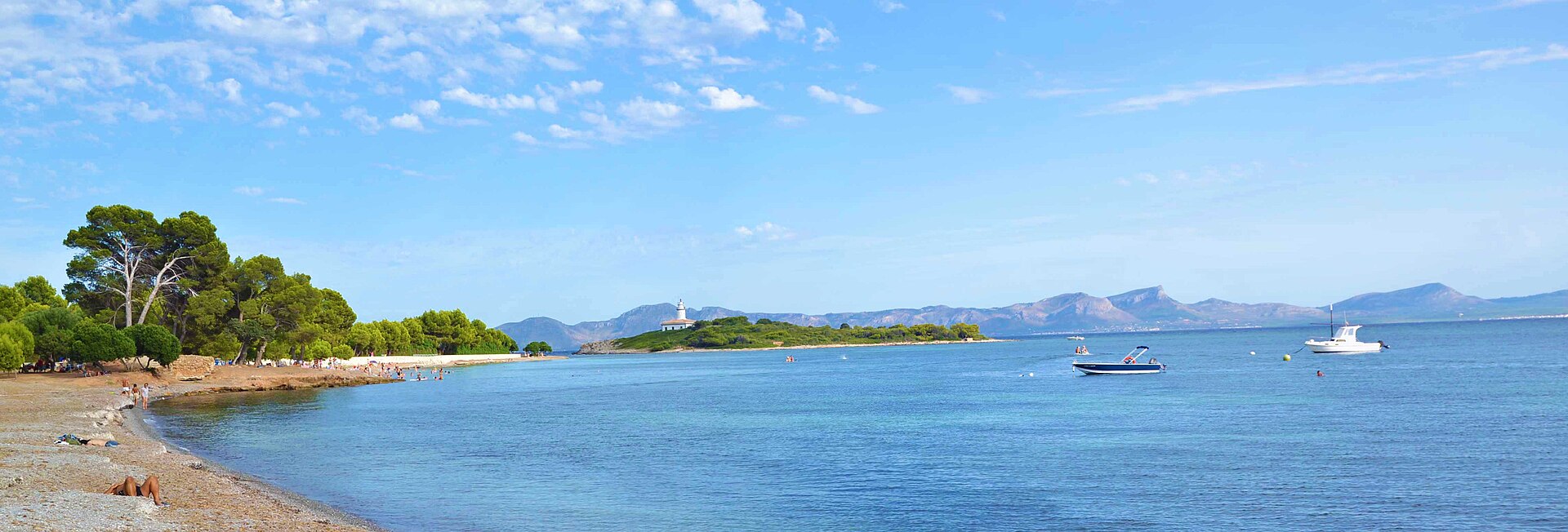 Alcanada Mallorca: rustig snorkelstrand met vuurtoreneilandje 3 Het langgerekte strand van Alcanada met pijnbomen tot aan de waterlijn en het vuurtoreneilandje in de verte