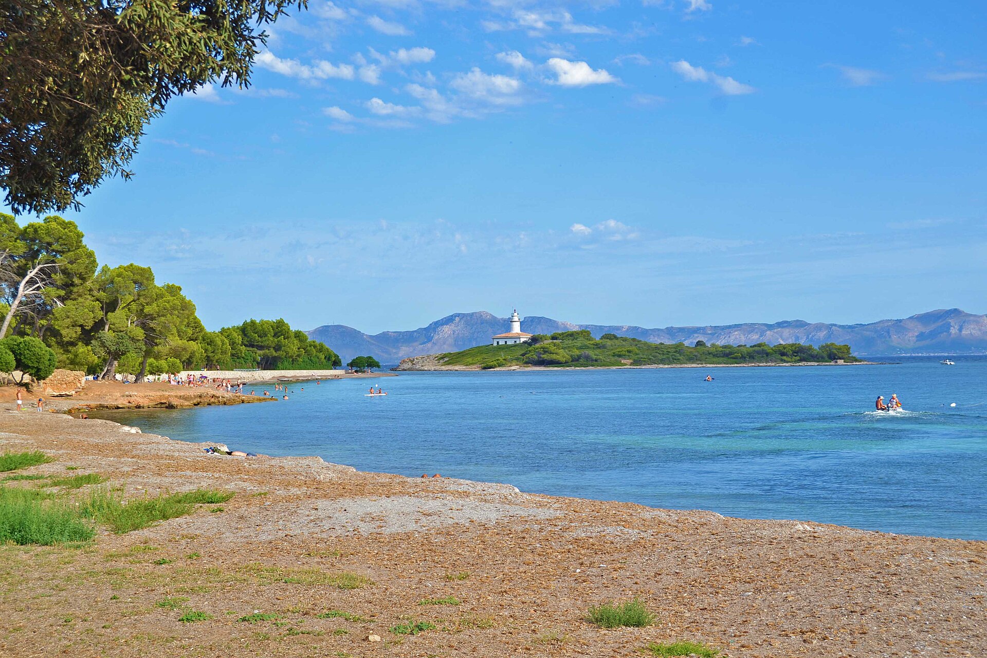 Alcanada Mallorca: rustig snorkelstrand met vuurtoreneilandje 4 Het kiezel- en steenstrand van Alcanada met helder blauw water en het eilandje Illa d'Alcanada met zijn vuurtoren