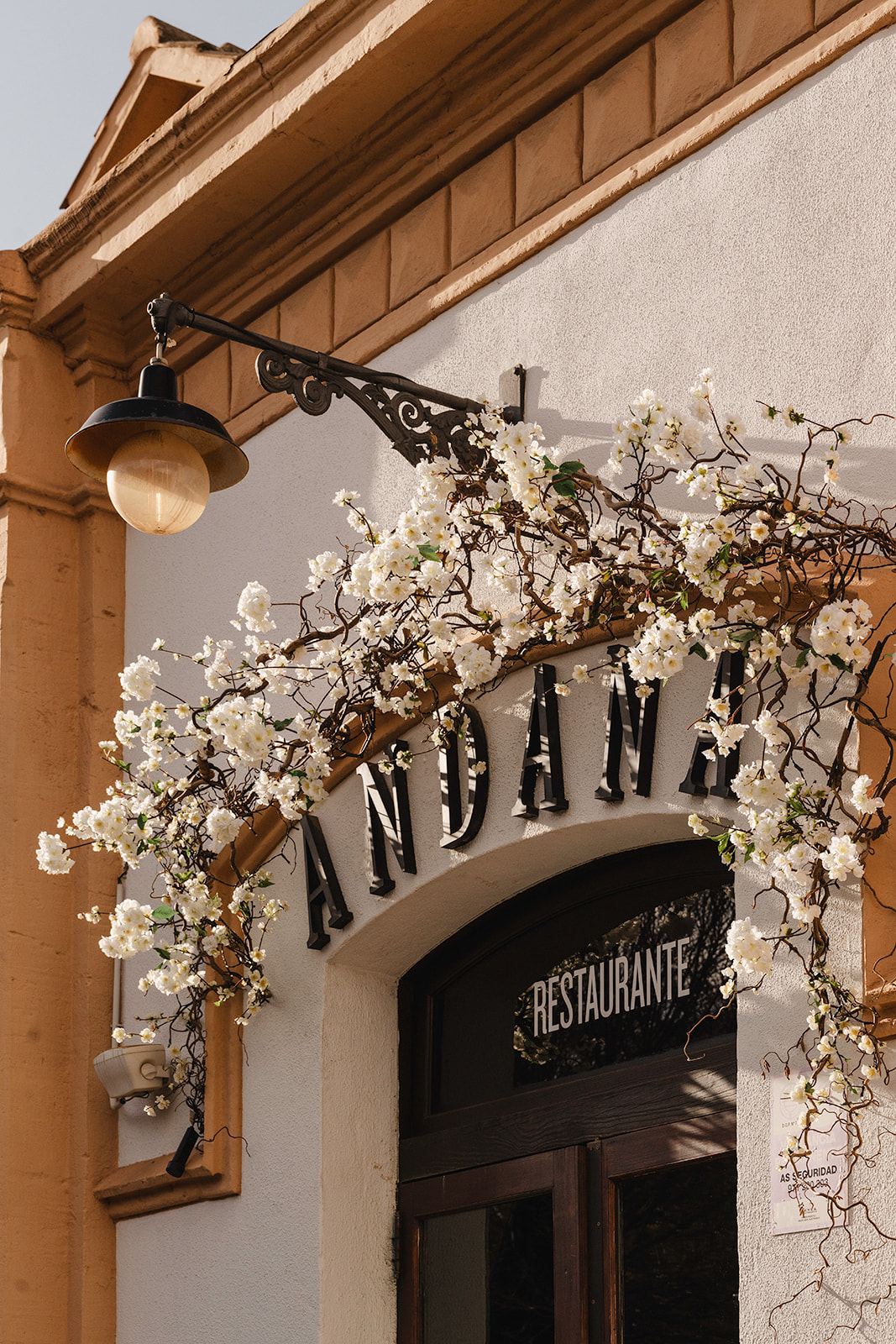 Andana Palma: eten in het eerste treinstation van Mallorca 1 De gevel van restaurant Andana in Palma met de naam in zwarte letters boven de boogdeur en witte bloesemtakken om de lantaarn
