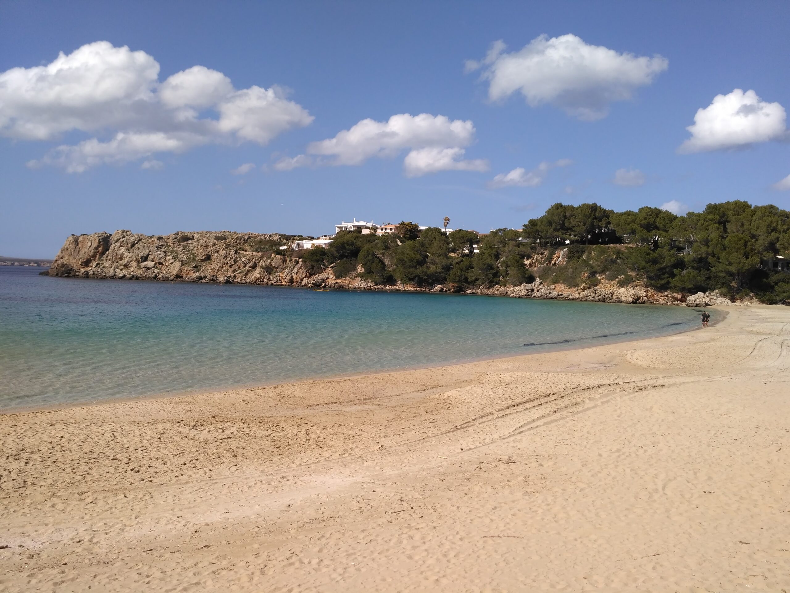 Geel zand en helder ondiep water in de baai van Arenal d'en Castell op een rustige dag buiten het seizoen