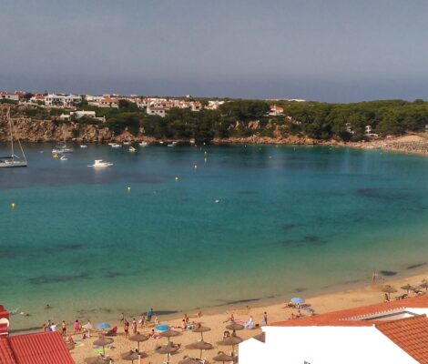 De bijna ronde baai van Arenal d'en Castell op Menorca met zeilboten voor anker en de zandboog aan de rechterkant