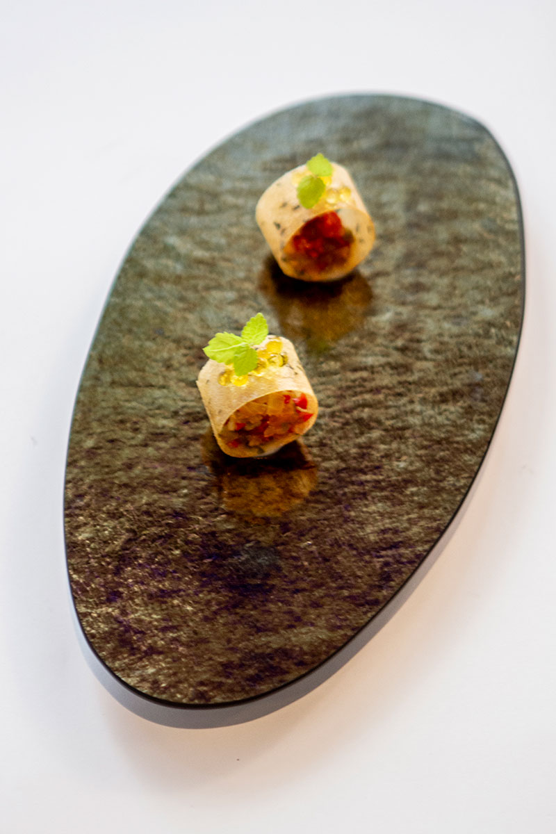 Twee gevulde hapjes met een blaadje kruid op een ovale leisteen schaal bij restaurant Aromata in Palma
