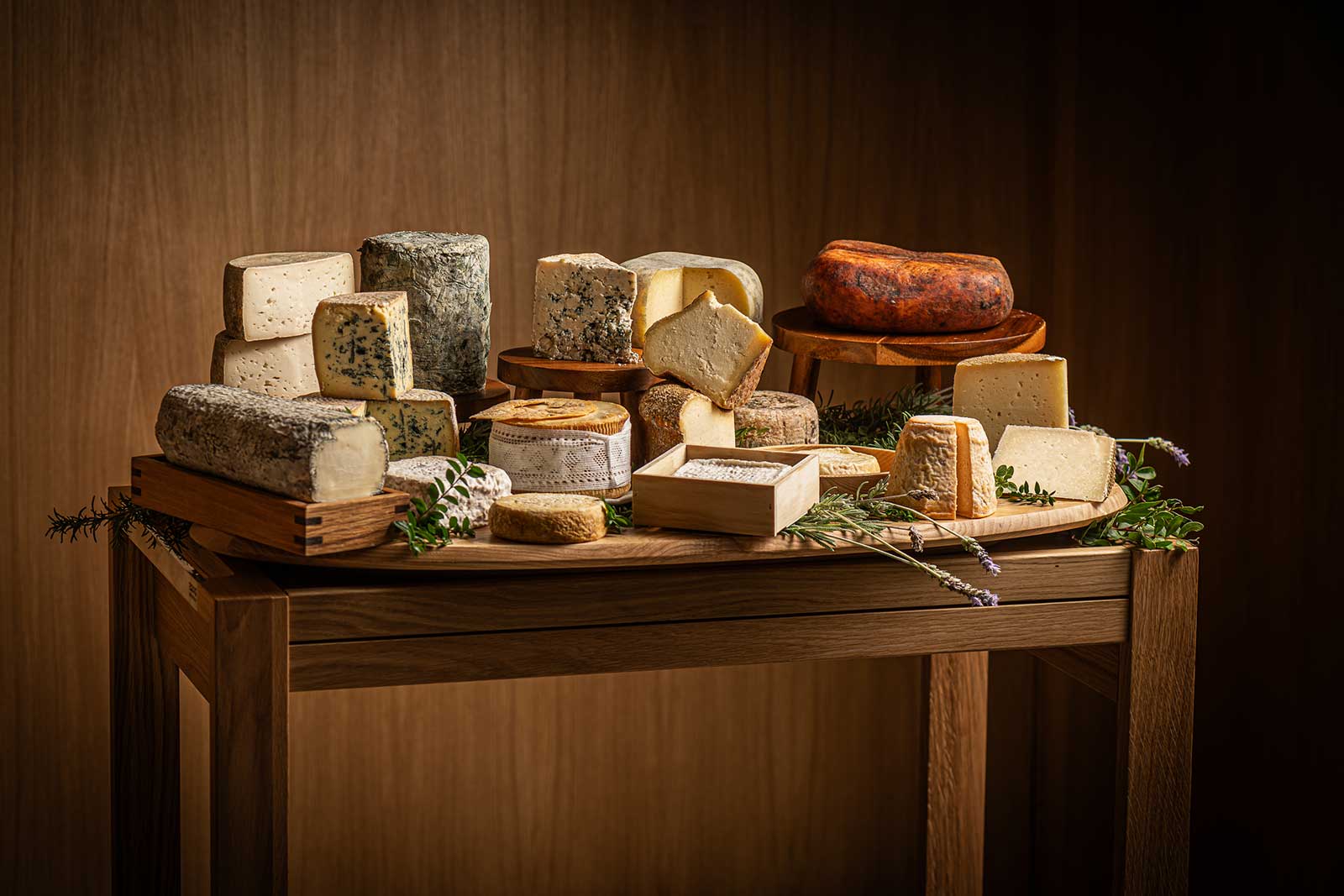 Houten tafel met een grote selectie Spaanse kazen en takjes kruiden, de kaaswagen van Aromata in Palma