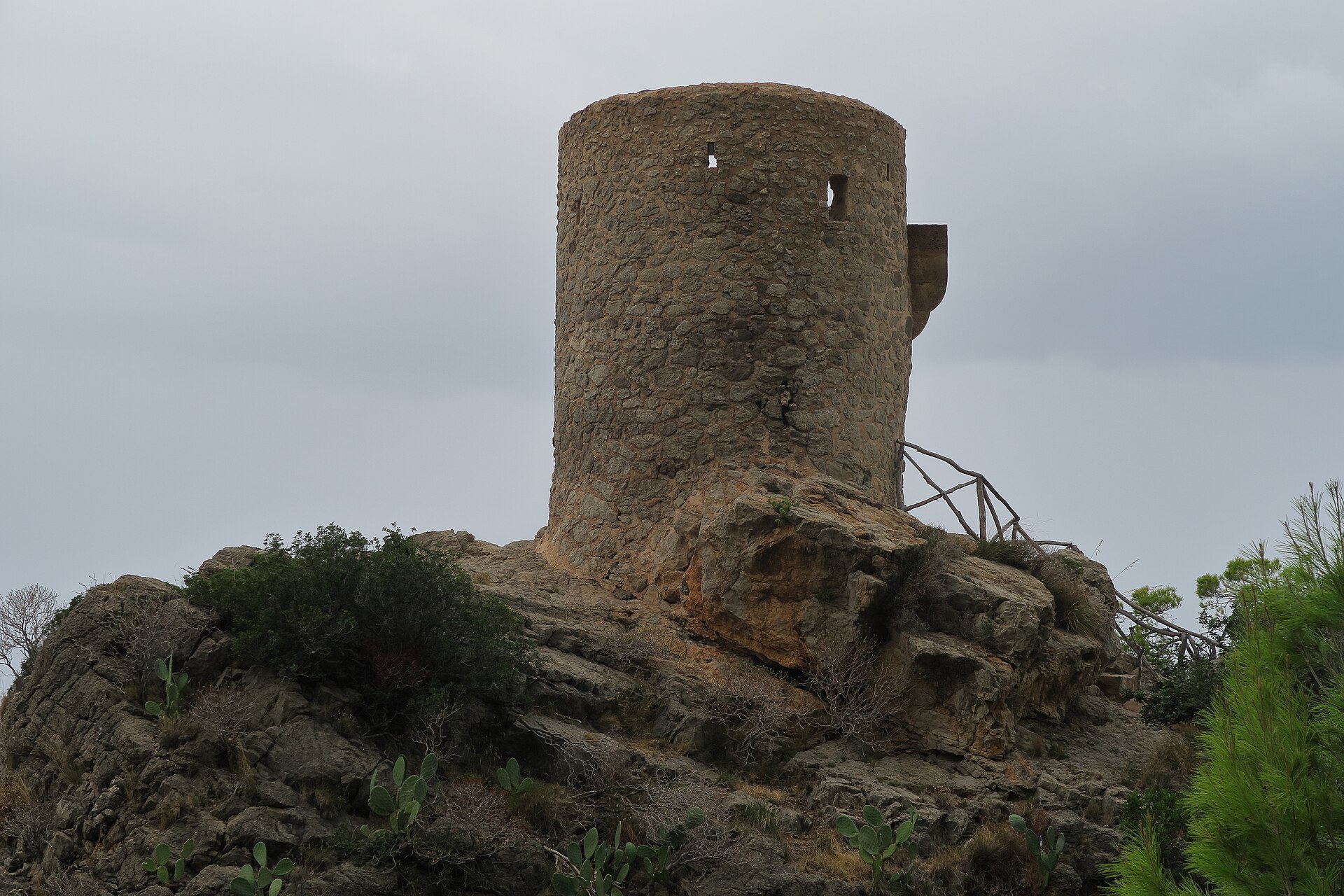 De ronde stenen wachttoren Torre des Verger op een rotspunt bij Banyalbufar, met een houten trapleuning ernaartoe