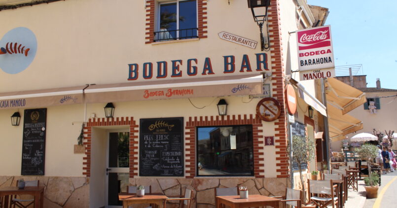 Bodega Barahona in Ses Salines: het visrestaurant dat ook Casa Manolo heet 1 De hoekgevel van Bodega Barahona in Ses Salines met de blauwe letters Bodega Bar, krijtborden met de visvangst en houten terrastafels op het plein