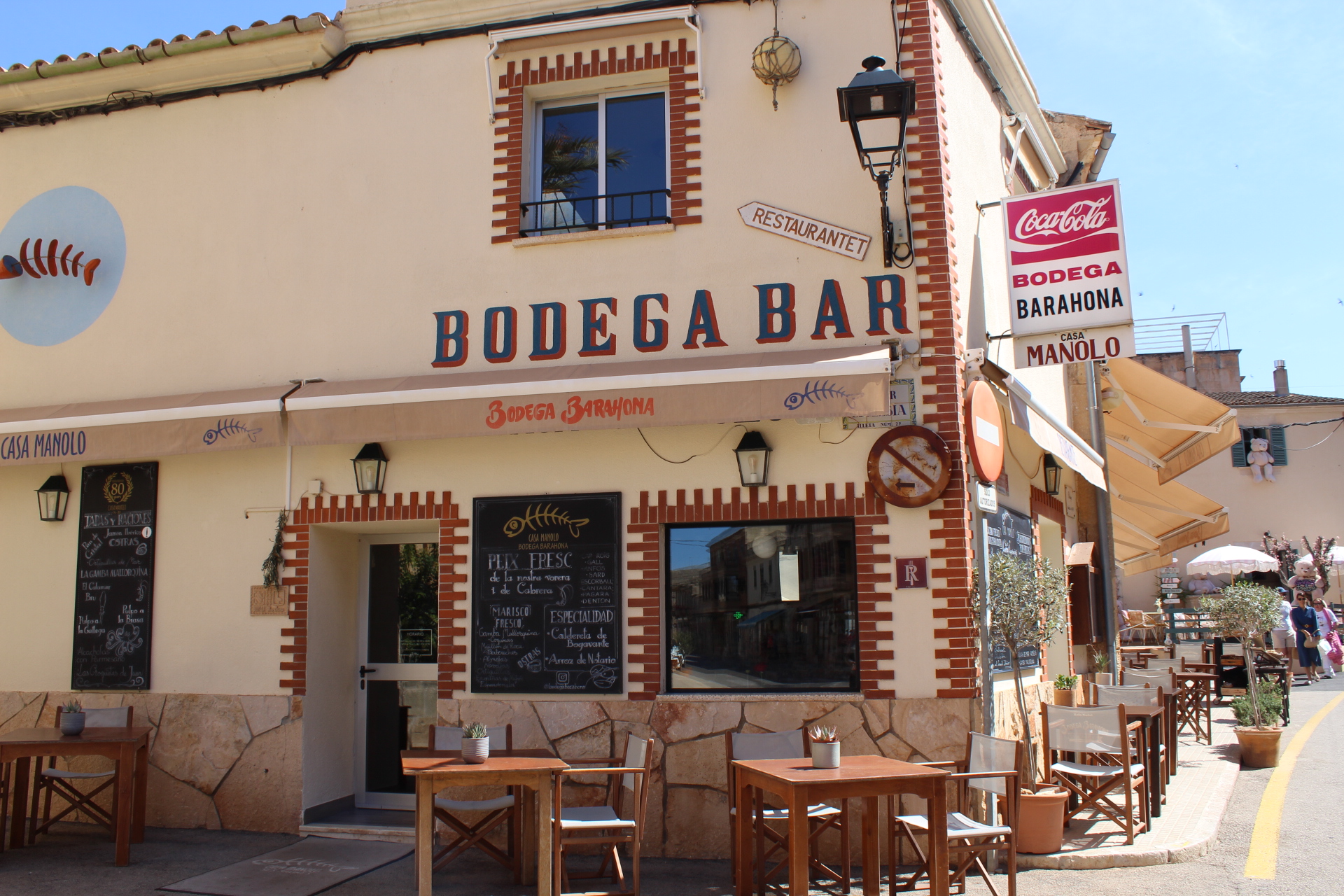 Bodega Barahona in Ses Salines: het visrestaurant dat ook Casa Manolo heet 1 De hoekgevel van Bodega Barahona in Ses Salines met de blauwe letters Bodega Bar, krijtborden met de visvangst en houten terrastafels op het plein