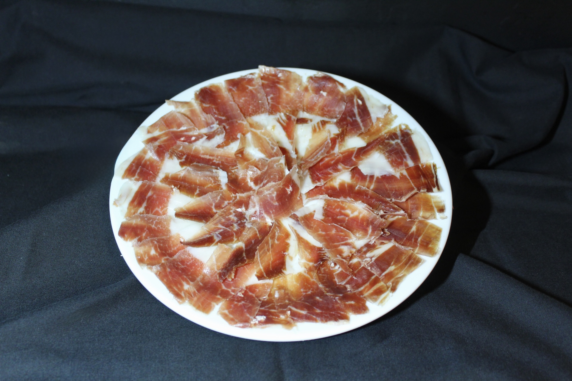 Bodega Barahona in Ses Salines: het visrestaurant dat ook Casa Manolo heet 5 Dungesneden Iberische ham waaiervormig uitgelegd op een witte schaal bij Bodega Barahona