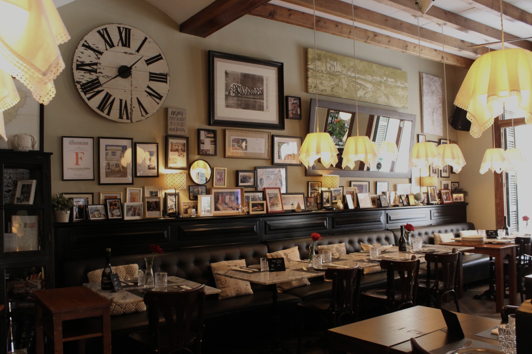 Bodega Barahona in Ses Salines: het visrestaurant dat ook Casa Manolo heet 2 De eetzaal van Bodega Barahona met een grote houten klok, een leren bank langs de muur en een plank vol ingelijste familiefoto's