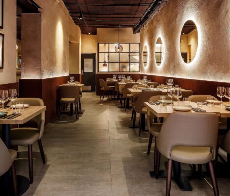 Bondo Cocina in Palma: Argentijnse keuken in een oude garage 2 De eetzaal van Bondo Cocina in Palma met lichte houten tafels, ovale nissen in de gepleisterde wand en ingelijste prenten