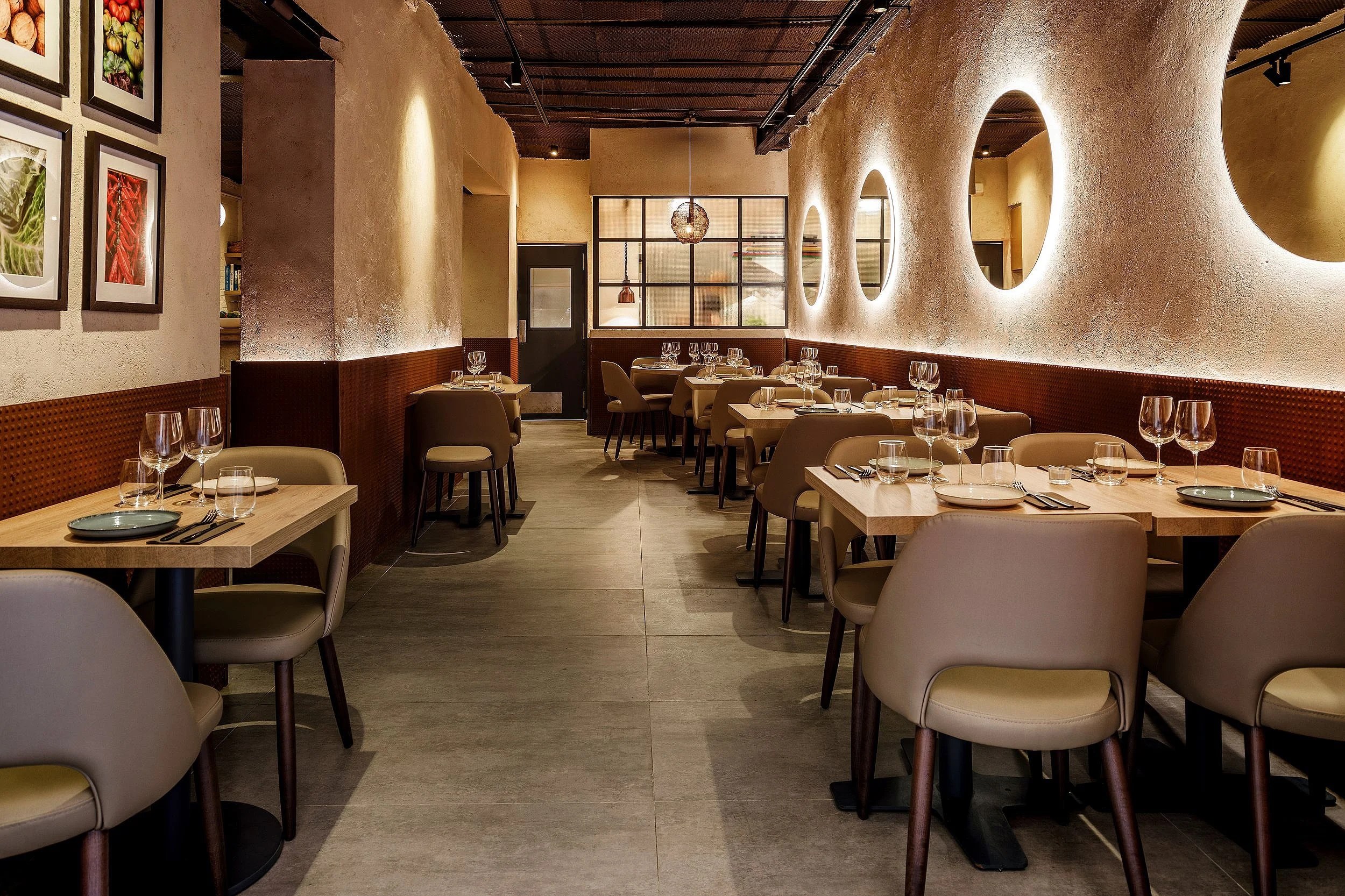 Bondo Cocina in Palma: Argentijnse keuken in een oude garage 1 De eetzaal van Bondo Cocina in Palma met lichte houten tafels, ovale nissen in de gepleisterde wand en ingelijste prenten