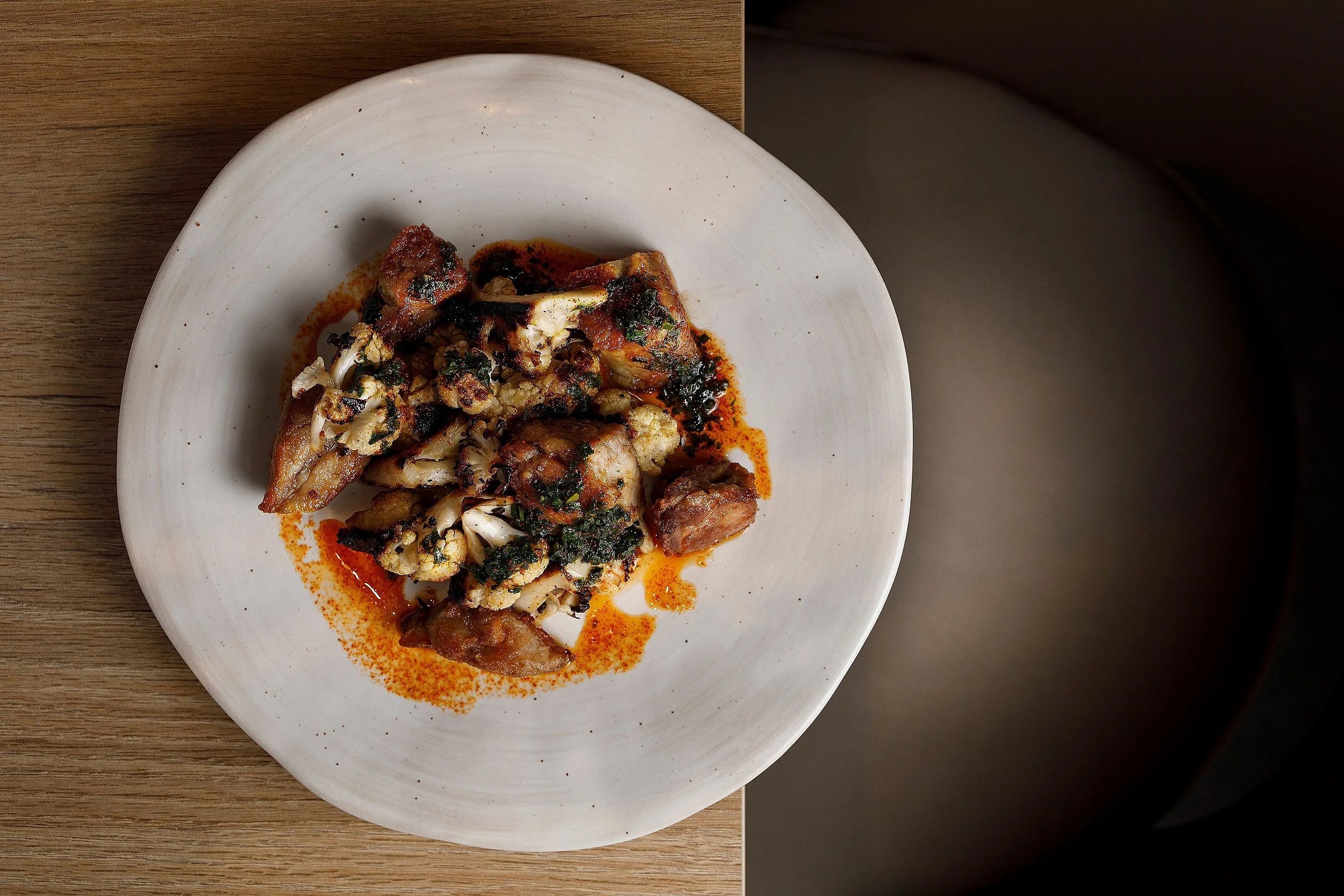 Bondo Cocina in Palma: Argentijnse keuken in een oude garage 2 Gegrild rundvlees met kruiden en saus op een licht aardewerken bord bij Bondo Cocina in Palma