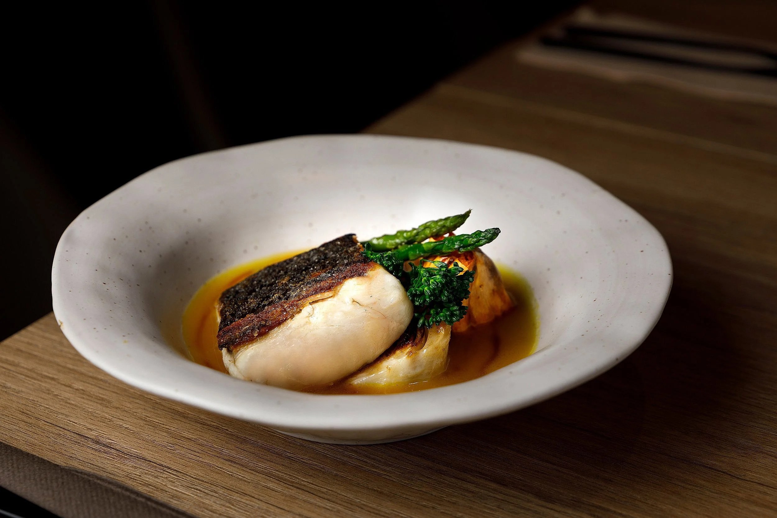 Bondo Cocina in Palma: Argentijnse keuken in een oude garage 3 Gegrilde witvis met asperges en aardappel in een diep wit bord bij Bondo Cocina in Palma
