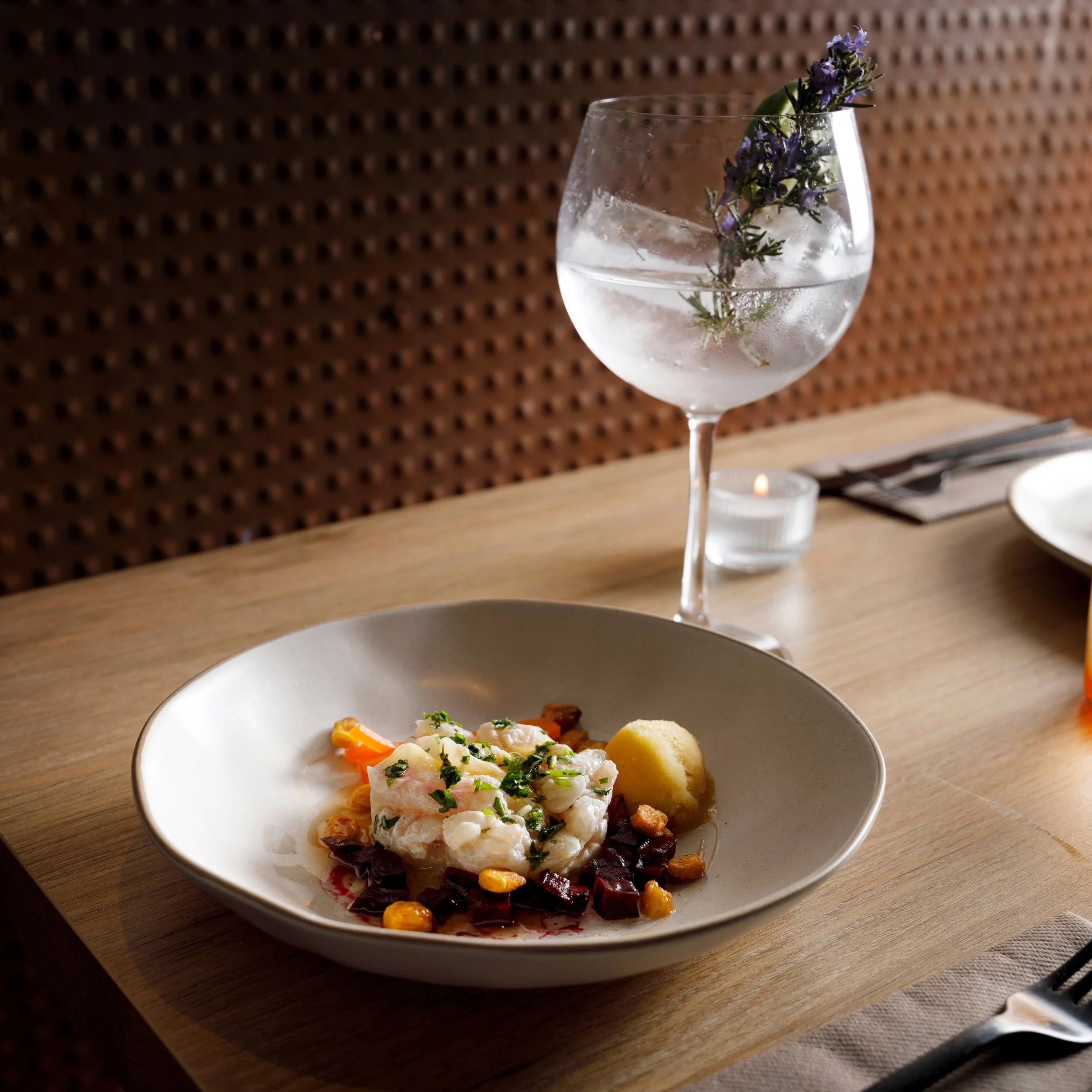 Bondo Cocina in Palma: Argentijnse keuken in een oude garage 5 Ceviche van witvis met biet en mais in een ondiepe kom, met een gin tonic ernaast, bij Bondo Cocina
