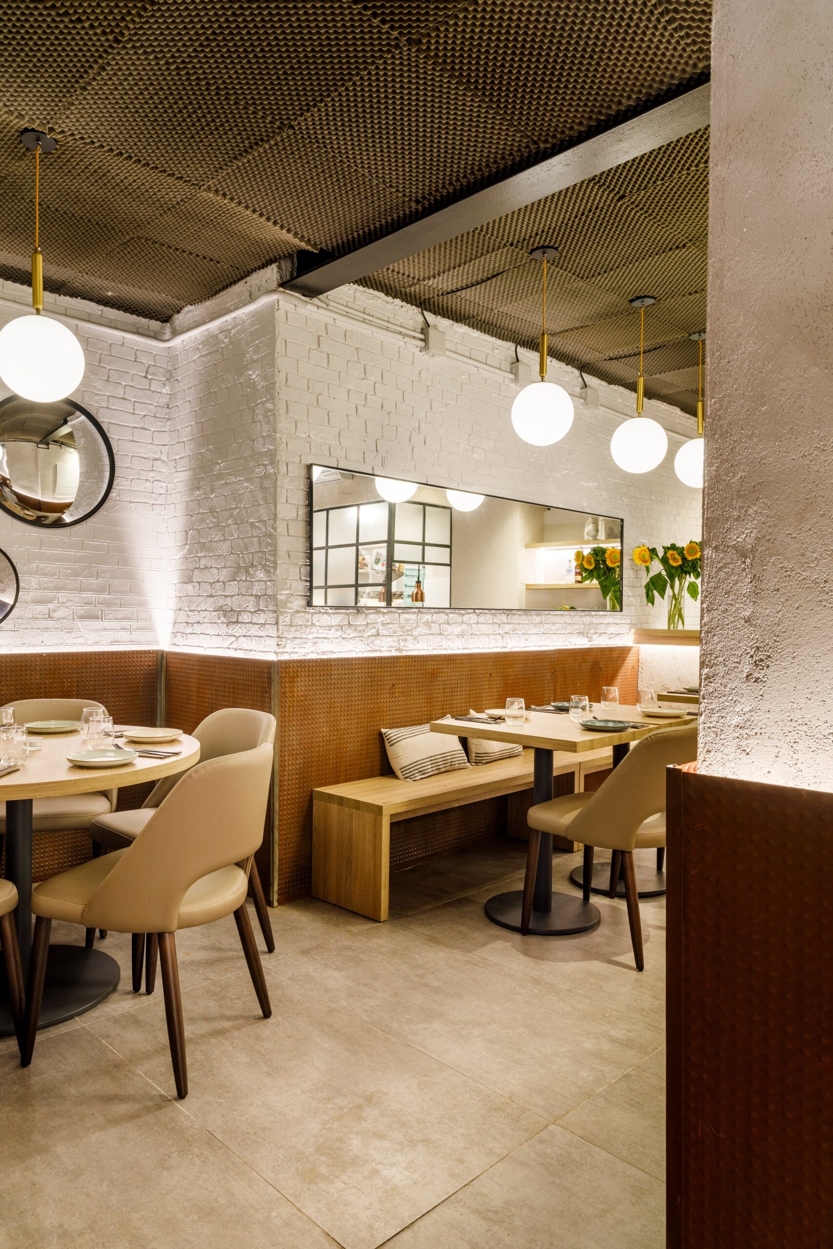 Bondo Cocina in Palma: Argentijnse keuken in een oude garage 7 Gedekte tafels en lichte stoelen in de voorste ruimte van restaurant Bondo Cocina in Palma, met bolvormige hanglampen