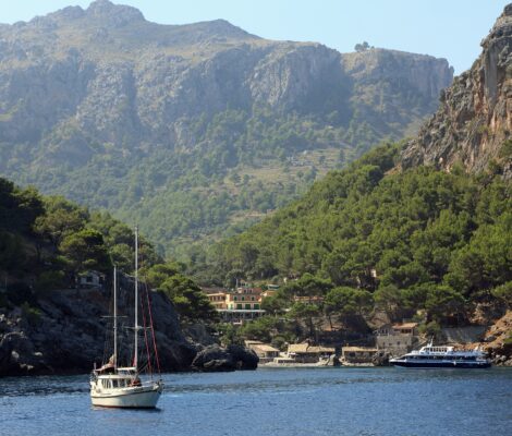 Excursieboot en zeilboot in de baai van Sa Calobra onder de bergen van de Serra de Tramuntana